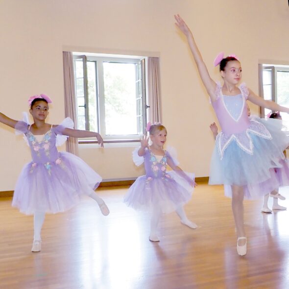 Drei Kinder unterschiedlichen Alters tanzen gemeinsam Ballett. Sie tragen zarte Ballettkleidchen in hellen Farben und passende Ballettschuhe. Mit konzentrierten Gesichtern und anmutigen Bewegungen bewegen sie sich im Einklang - jede auf ihre eigene Art, aber vereint im Tanz. Ihre Körperhaltung zeigt Freude, Spannung und Stolz.